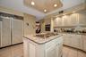 Kitchen with light stone counters, light tile patterned floors, a kitchen island, recessed lighting, and oven