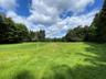 View of grassy yard featuring a view of trees and a rural view