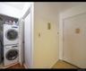 Laundry room with stacked washer / dryer, light tile patterned floors, and electric panel