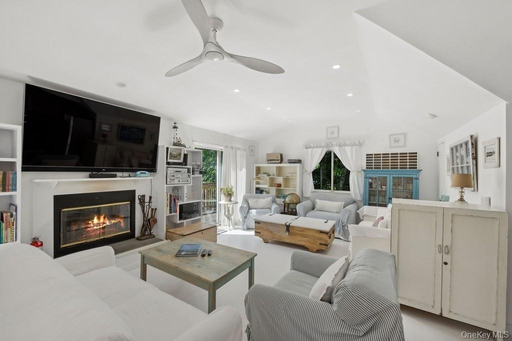 Living area featuring a glass covered fireplace, lofted ceiling, recessed lighting, and ceiling fan