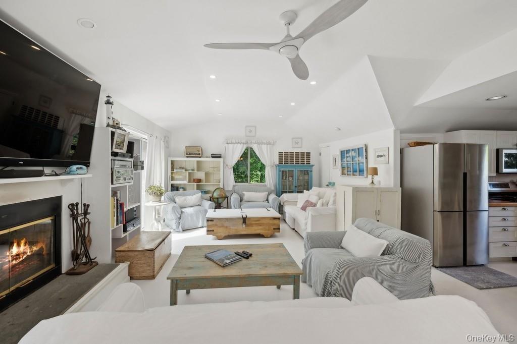 Living area featuring vaulted ceiling, recessed lighting, a glass covered fireplace, and ceiling fan