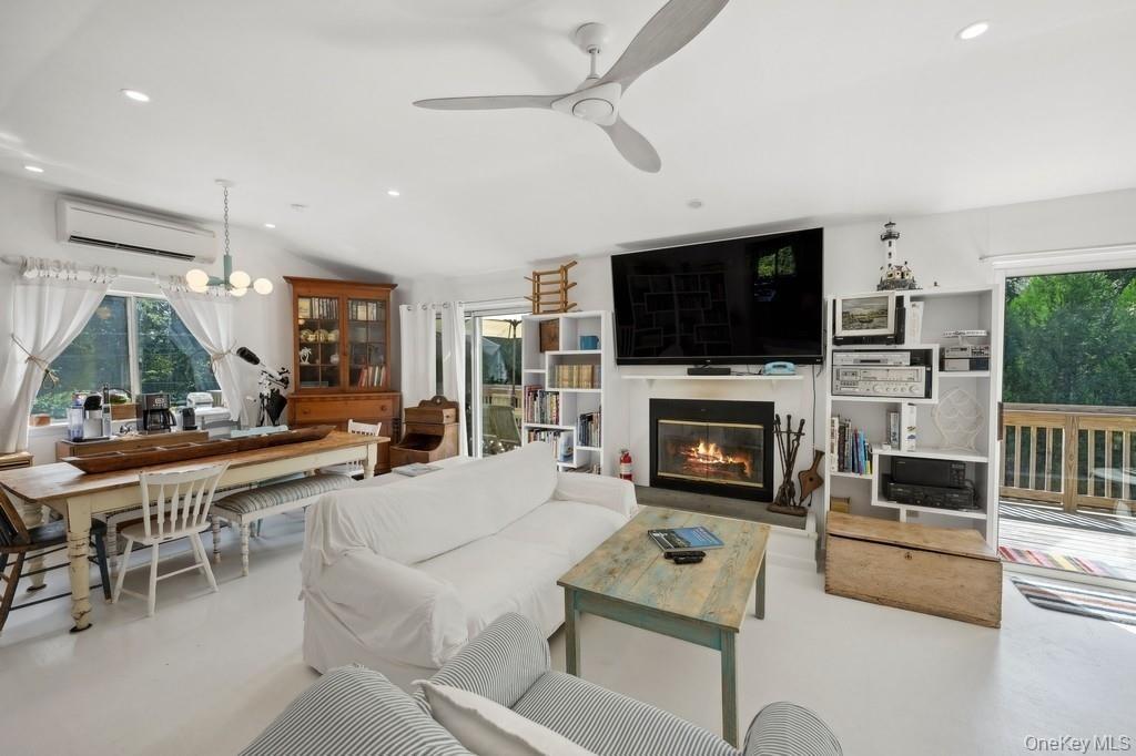 Living room featuring recessed lighting, a glass covered fireplace, an AC wall unit, a chandelier, and ceiling fan