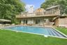 Rear view of property with a patio, a wooden deck, an outdoor pool, and a chimney