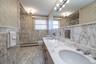 Full Bathroom with double vanity, a shower with attractive marble finish walls and floors and whirlpool tub/shower.