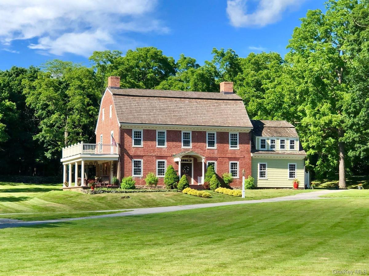 View of front of property with a front lawn, a chimney, and brick siding