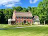 View of front of property with a front lawn, a chimney, and brick siding