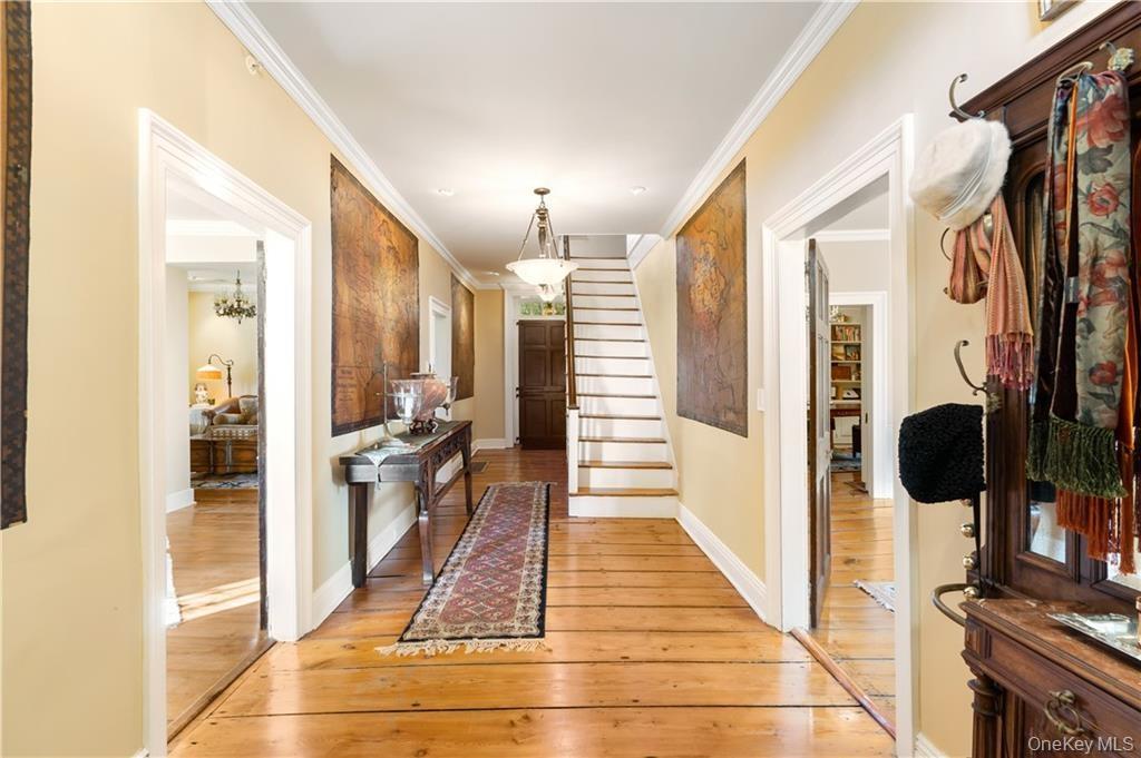 Corridor featuring light wood-style flooring, ornamental molding, and stairs