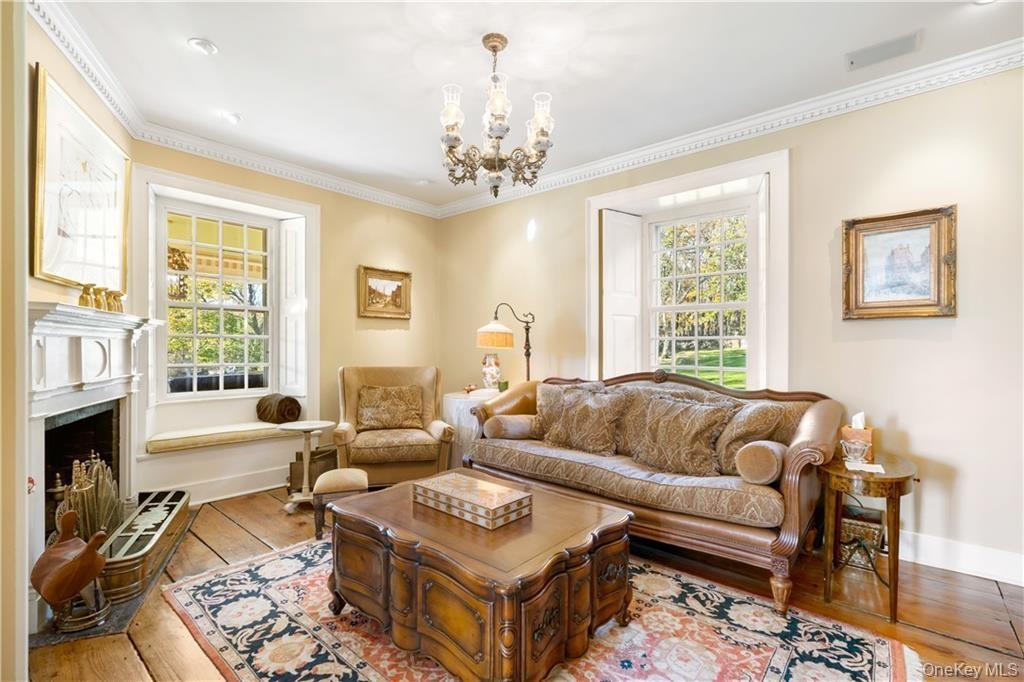 Living area featuring a chandelier, hardwood / wood-style flooring, ornamental molding, and a fireplace