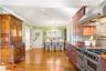 Kitchen with wall chimney exhaust hood, a chandelier, light wood finished floors, pendant lighting, and crown molding