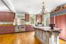 Kitchen with high quality appliances, wall chimney exhaust hood, hanging light fixtures, a chandelier, and crown molding