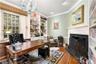 Office space featuring light wood-style flooring, crown molding, a fireplace with flush hearth, and a chandelier