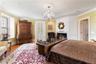 Bedroom with crown molding, a chandelier, wood finished floors, and a lit fireplace