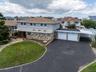 View of front of Home featuring asphalt driveway, stone siding, and a front yard curb appeal.