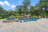 Outdoor pool featuring a patio area, an in-ground hot tub, and view of wooded area