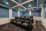 Cinema featuring a decorative wall, wainscoting, dark colored carpet, coffered ceiling, and beam ceiling