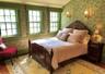 Bedroom with wallpapered walls, wood finished floors, and a baseboard heating unit