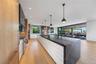 Kitchen with modern cabinets, light wood-style floors, dark stone countertops, decorative light fixtures, and floor to ceiling windows