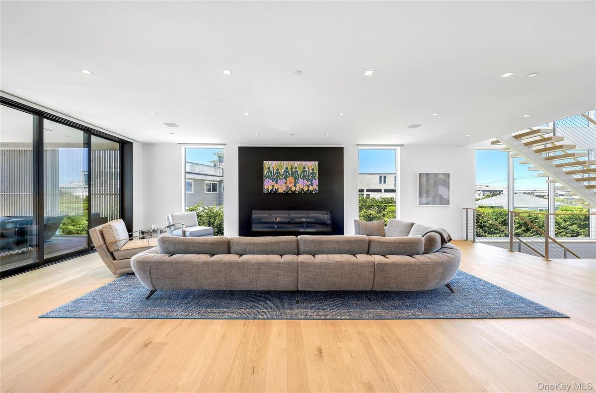 Living area with floor to ceiling windows, wood finished floors, recessed lighting, and stairs