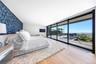 Bedroom featuring expansive windows, light wood-type flooring, access to outside, wallpapered walls, and an accent wall