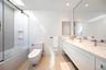 Bathroom featuring tile walls, combined bath / shower with glass door, vanity, and dark speckled floor