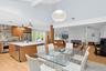 Dining room with light wood-style floors, beam ceiling, a fireplace, beverage cooler, and high vaulted ceiling
