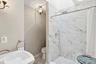 Bathroom featuring a shower stall and light marble finish flooring