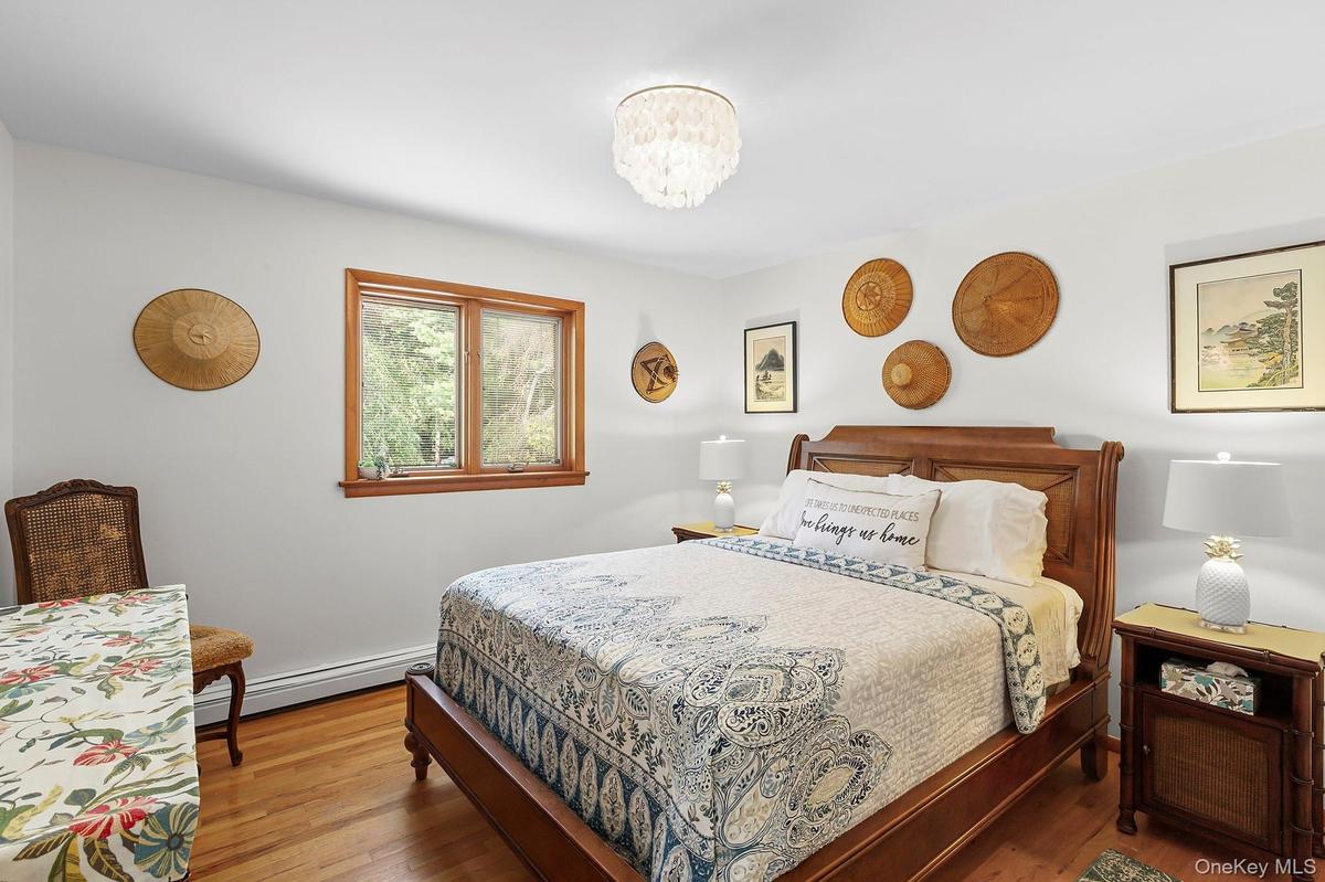 Bedroom with wood finished floors, baseboard heating, and a chandelier