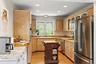 Kitchen with stainless steel appliances, glass insert cabinets, light wood-style floors, light brown cabinets, and recessed lighting