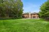 Rear view of house featuring an outdoor pool, a patio area, a lawn, and stone siding
