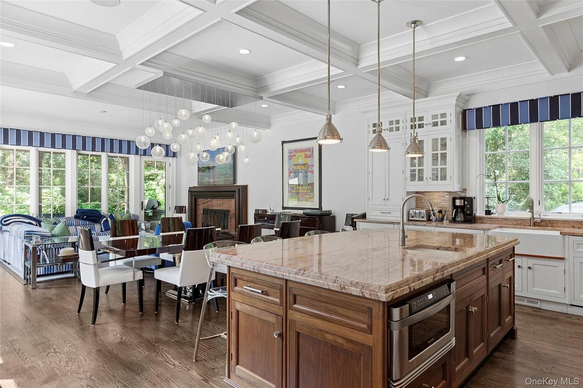 Kitchen featuring glass insert cabinets, a kitchen island with sink, dark wood-type flooring, light stone countertops, and beamed ceiling