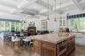 Kitchen featuring glass insert cabinets, a kitchen island with sink, dark wood-type flooring, light stone countertops, and beamed ceiling