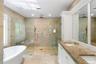 Bathroom featuring a soaking tub, a shower stall, tile walls, double vanity, and recessed lighting