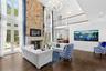 Living room with plenty of natural light, dark wood finished floors, a large fireplace, a chandelier, and a towering ceiling