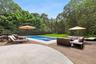 View of pool featuring a deck, an outdoor hangout area, a lawn, a pool with connected hot tub, and a view of trees