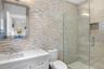 Full bath with tile walls, a stall shower, vanity, and backsplash