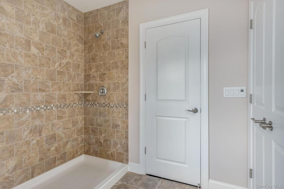 Bathroom with baseboards and a tile shower
