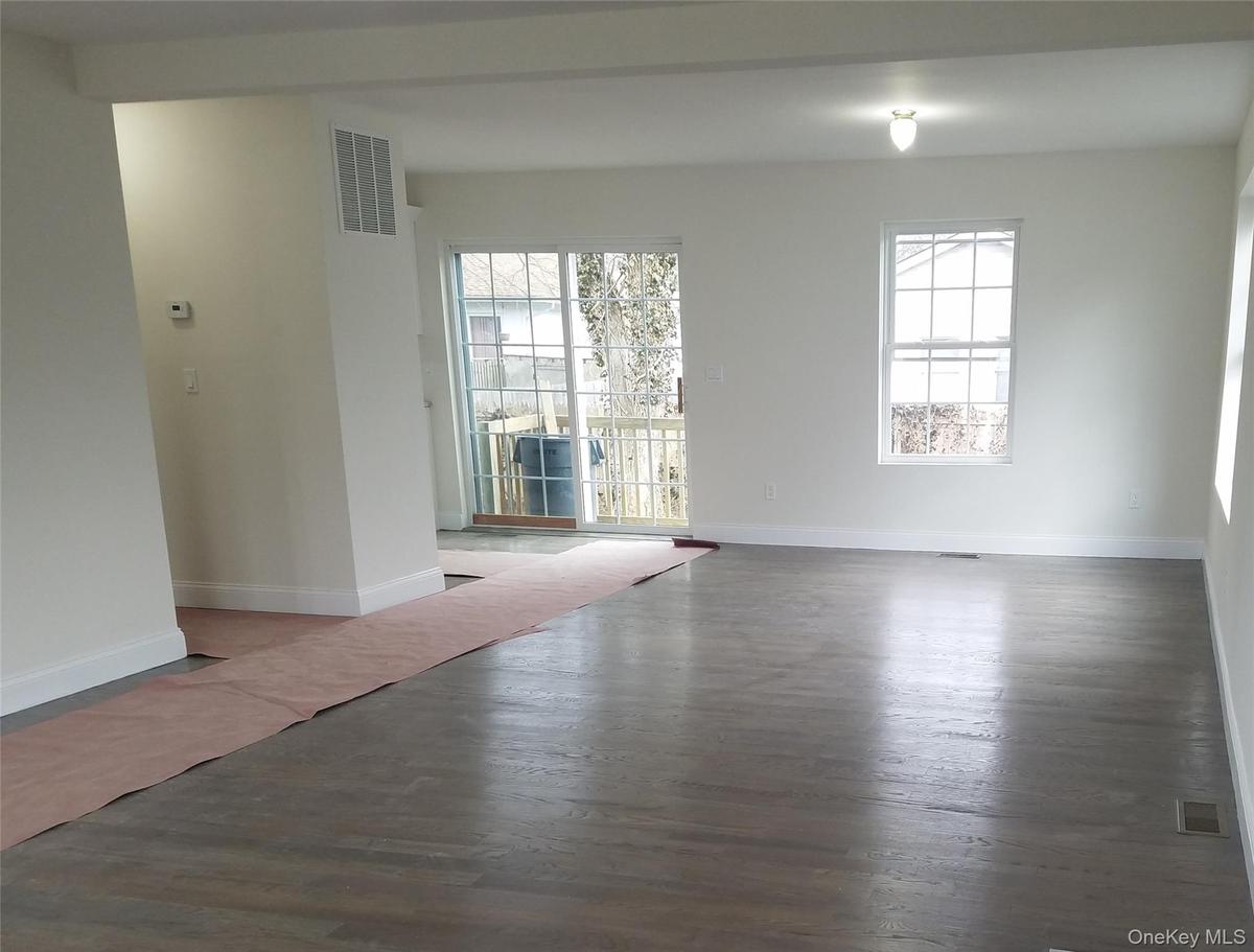 Unfurnished room with wood finished floors, visible vents, and baseboards