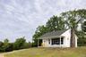 View of front of property featuring a front lawn, a chimney, roof with shingles, and covered porch