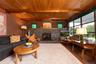 Living room featuring wooden ceiling with exposed beams, a stone fireplace, and wood finished floors