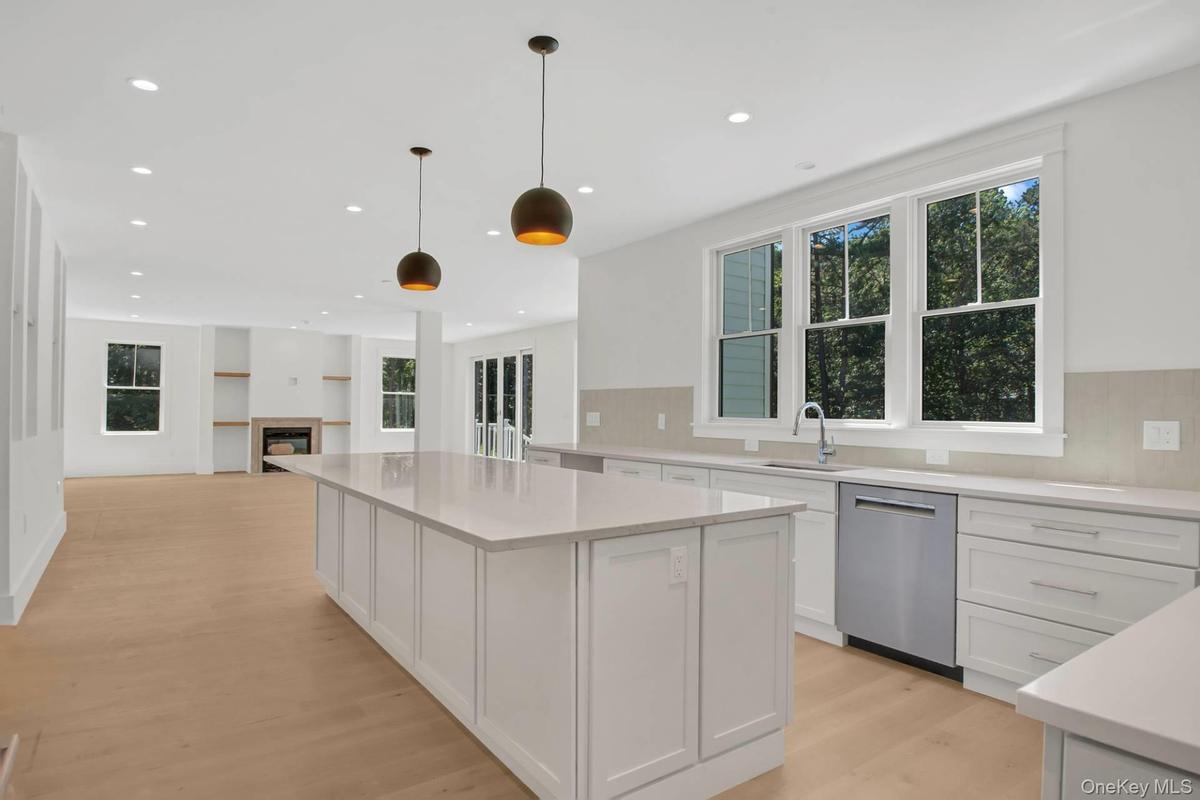 Kitchen featuring white cabinets, hanging light fixtures, stainless steel dishwasher, recessed lighting, and light wood-style floors