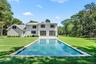 Rear view of property with a lawn, a patio, an outdoor pool, and board and batten siding