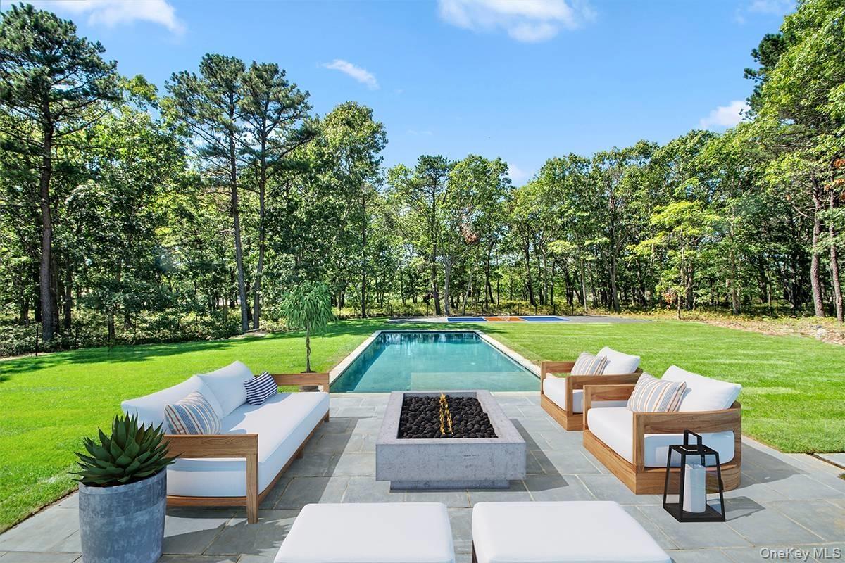 View of swimming pool featuring an outdoor living space with a fire pit, a lawn, a patio area, and view of scattered trees