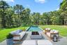 View of swimming pool featuring an outdoor living space with a fire pit, a lawn, a patio area, and view of scattered trees