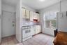 Kitchen with white appliances, light countertops, backsplash, light flooring, and open shelves