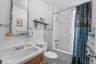 Bathroom featuring shower / bath combo with shower curtain, tile walls, and vanity