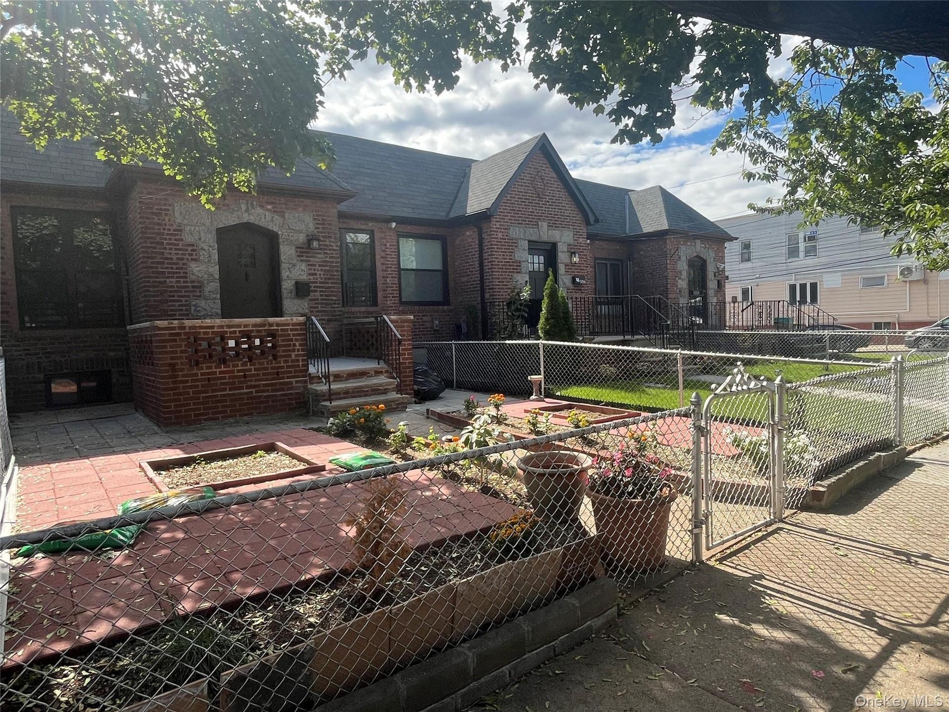 English style home with a gate, a fenced front yard, brick siding, and a patio area