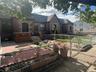 English style home with a gate, a fenced front yard, brick siding, and a patio area