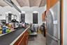 Kitchen with appliances with stainless steel finishes, finished concrete flooring, brown cabinets, and brick ceiling