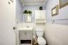 Half bath with crown molding, toilet, and wainscoting