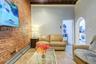 Tiled living area featuring brick wall, a baseboard heating unit, beamed ceiling, arched walkways, and washer / clothes dryer